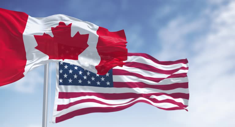 canada and american national flags waving in the wind on a c 1 3