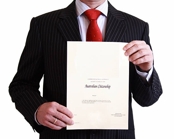 man in black suit holding australian citizenship certificate177513552